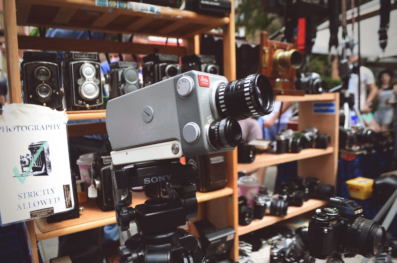 A variety of vintage cameras displayed on a market stall with customers browsing.